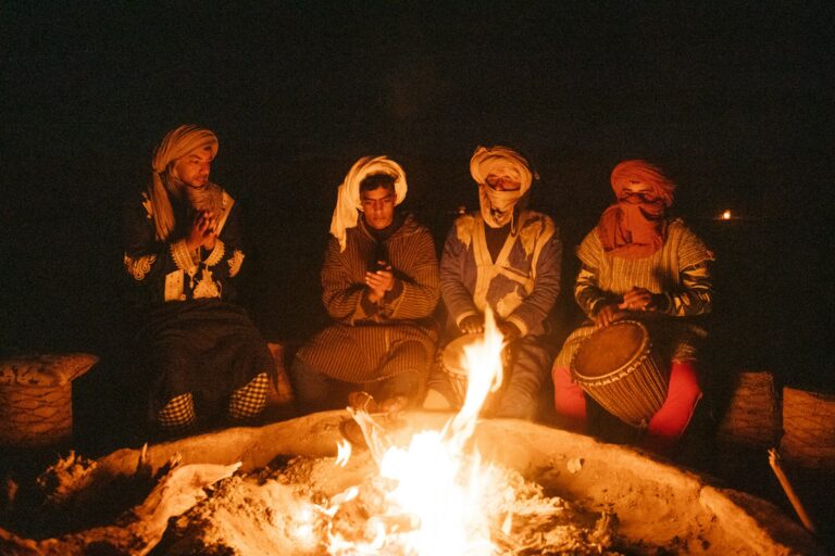 Travelers gathered around a campfire in the evening at a desert camp