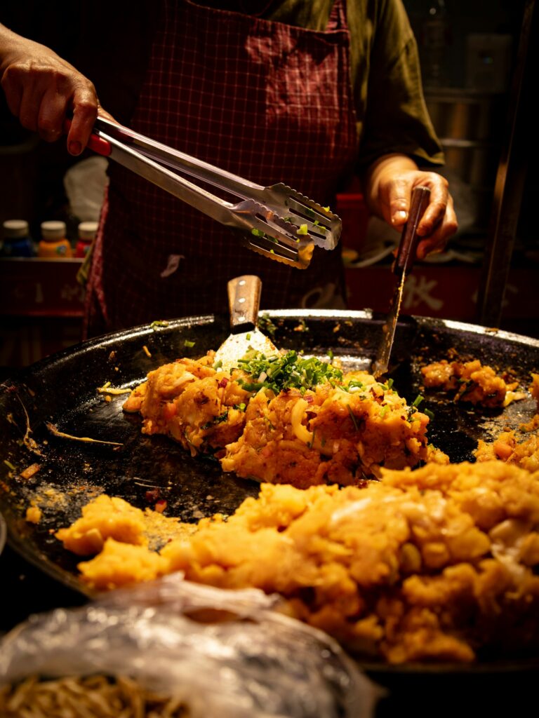 Cook preparing and garnishing a dish in a large pan during a cooking class