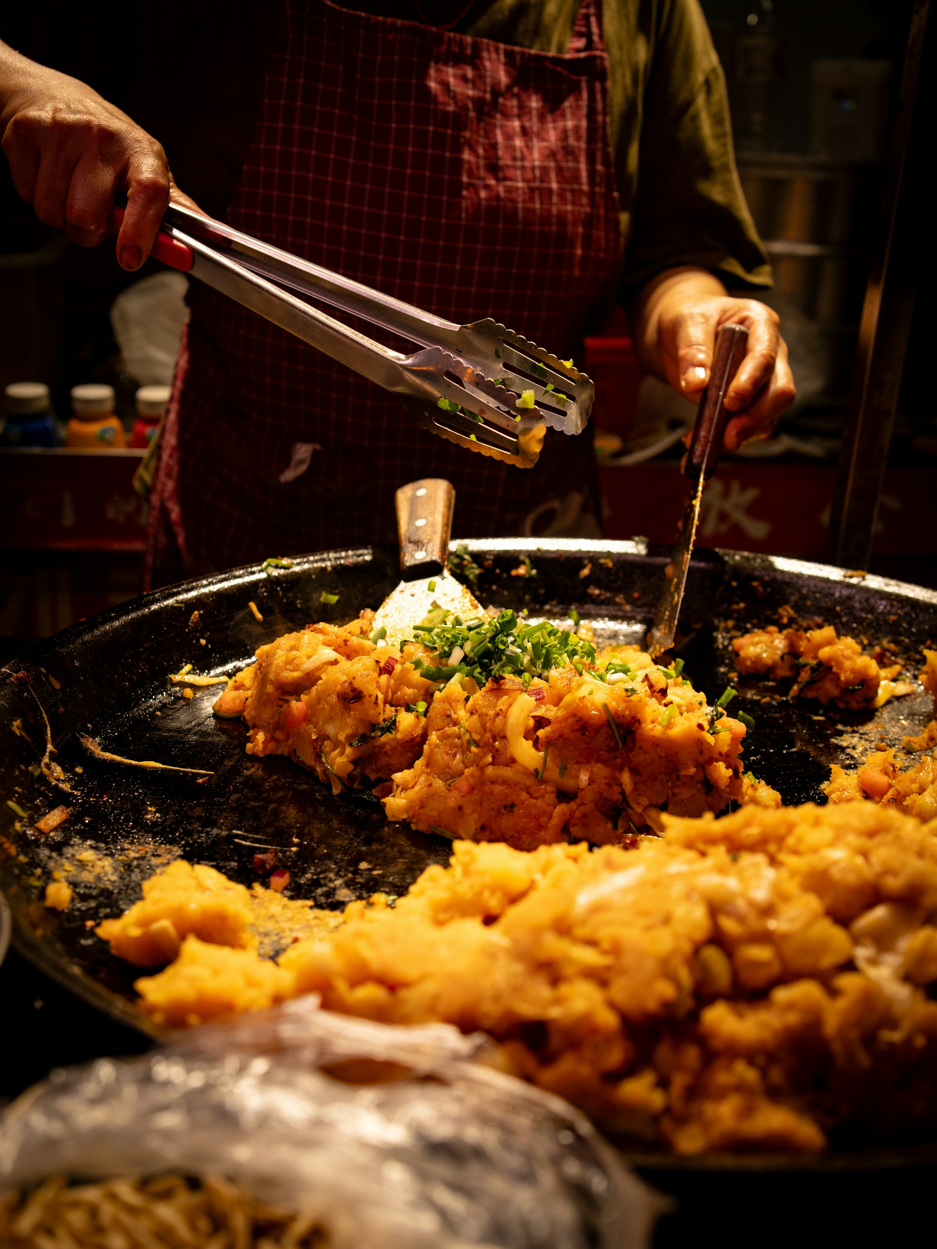 Cook preparing and garnishing a dish in a large pan during a cooking class