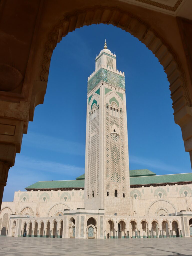 View of a mosque minaret framed by a carved Moroccan archway