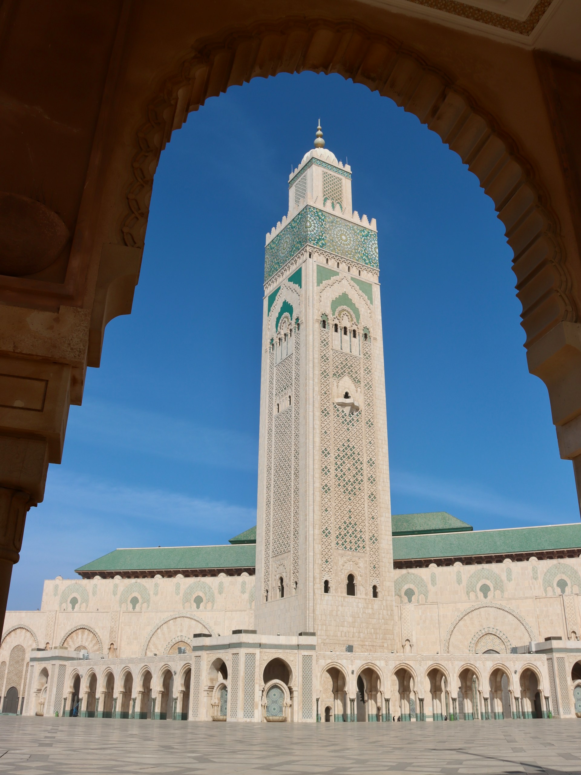 View of a mosque minaret framed by a carved Moroccan archway