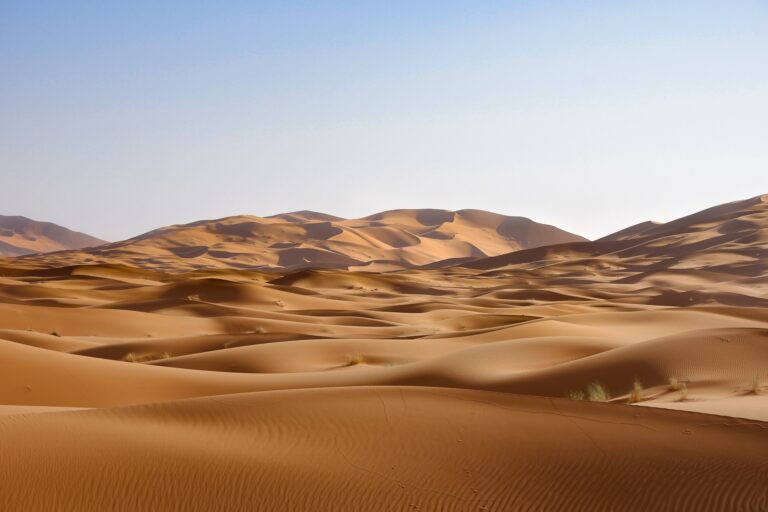 Rolling Sahara sand dunes under a clear blue sky in southern Morocco