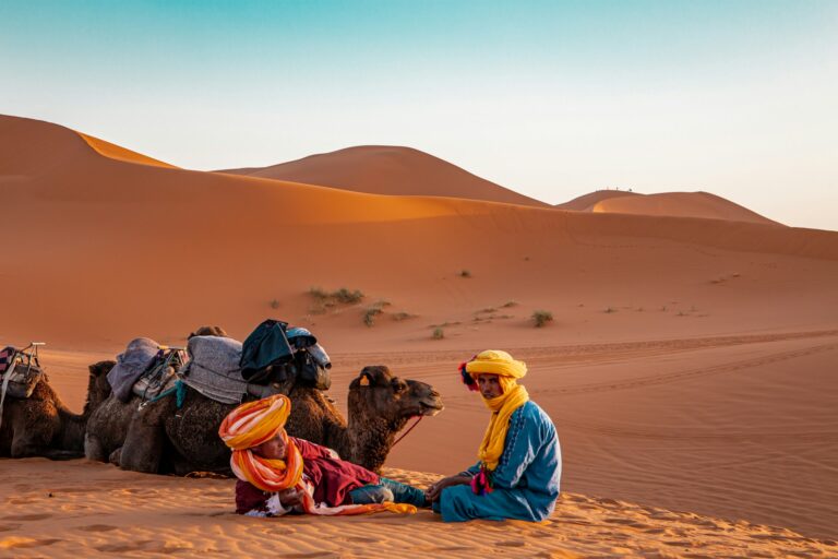 Berber guide in a yellow robe resting on the golden Sahara dunes near Merzouga